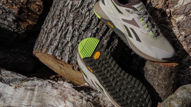 Grey and black Reebok shoes sit on chopped wood.